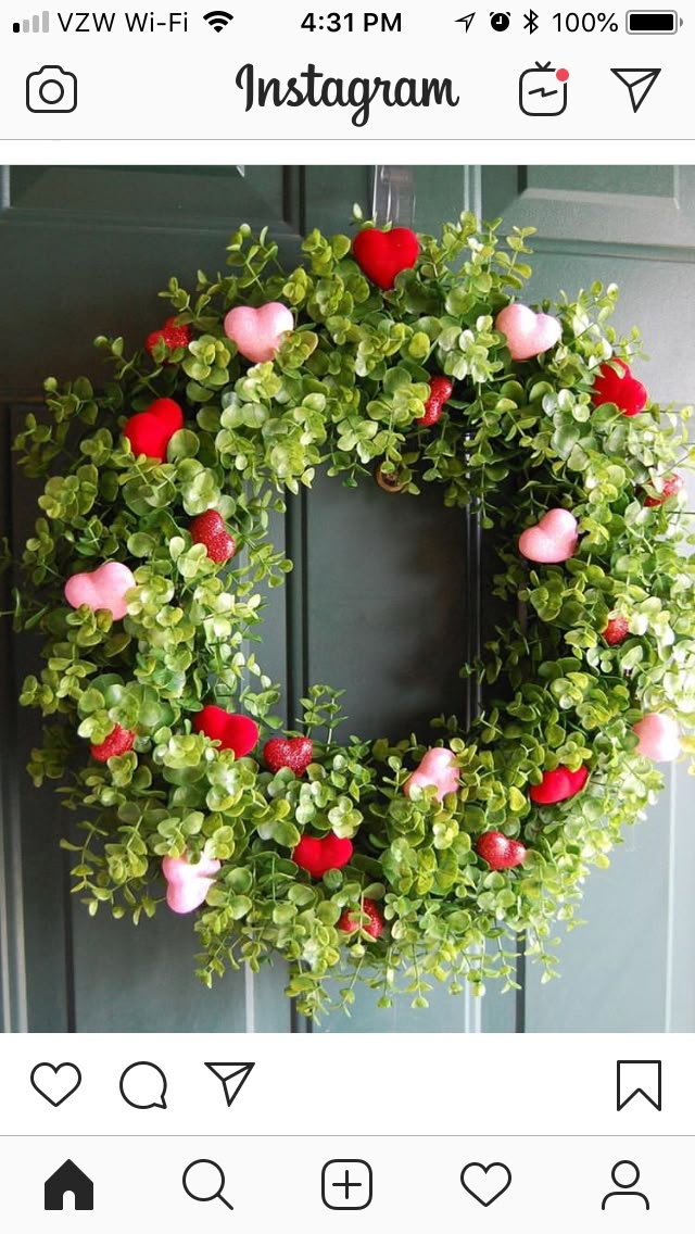 a wreath with hearts and greenery hanging on the front door for valentine's day