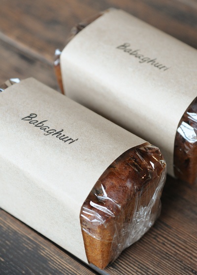 two pieces of bread wrapped in plastic wrap sitting on top of a wooden table next to each other