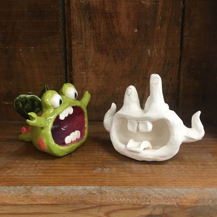 two ceramic figurines sitting on top of a wooden table