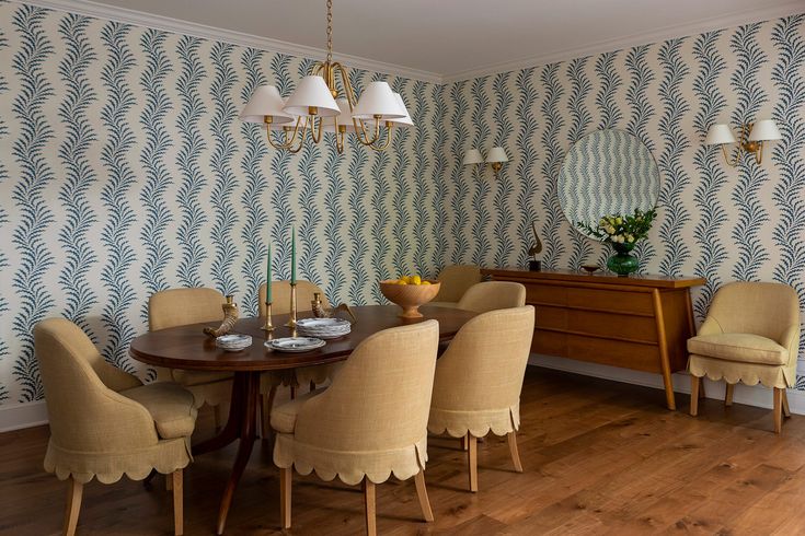 a dining room table and chairs in front of a wallpapered wall