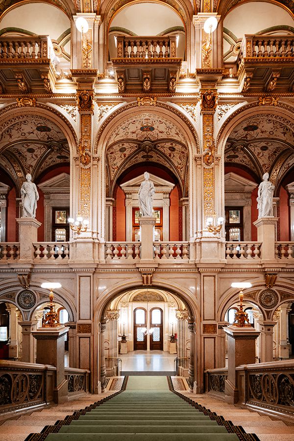 an ornate building with stairs and statues on the walls, along with green carpeting