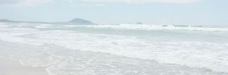 two people walking on the beach with surfboards