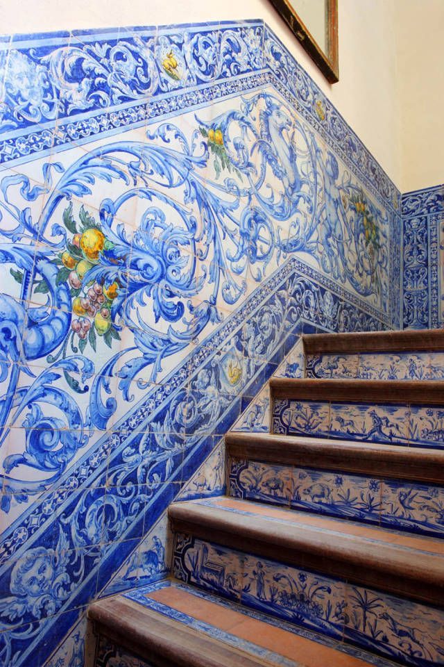 some blue and white tiles on the side of a stair case next to a mirror