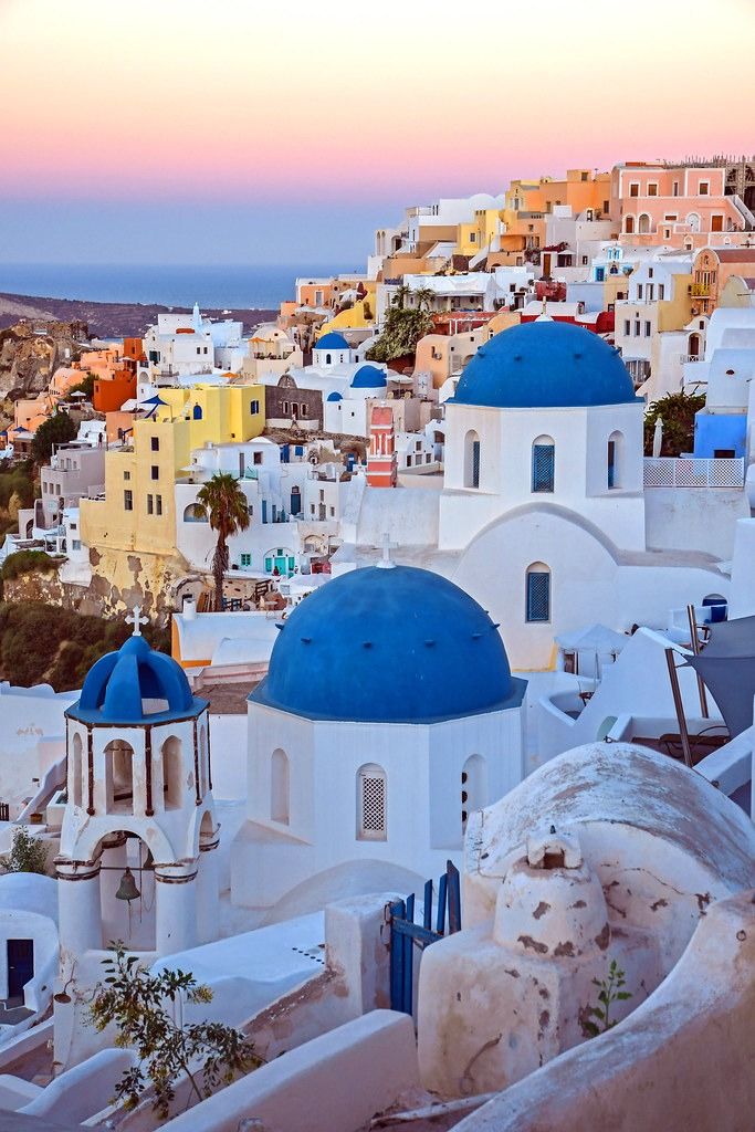 the sun is setting over some white buildings with blue domes