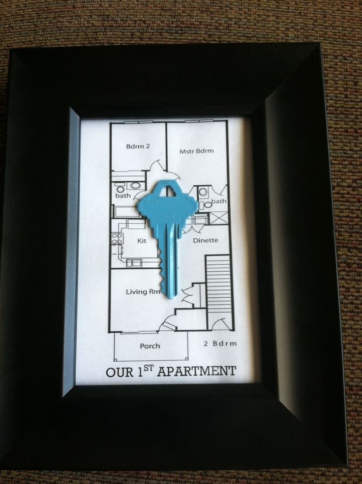 a blue key hangs in the middle of a black frame on a carpeted floor