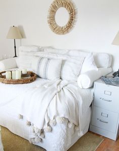 a white bed sitting next to a lamp on top of a wooden floor