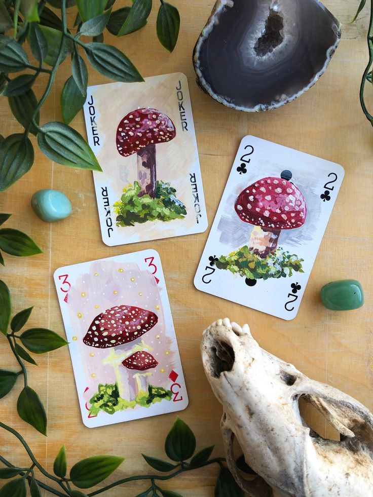 three cards with mushrooms on them next to some plants