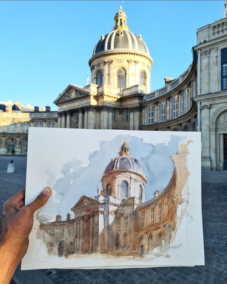 a person holding up a drawing in front of a building