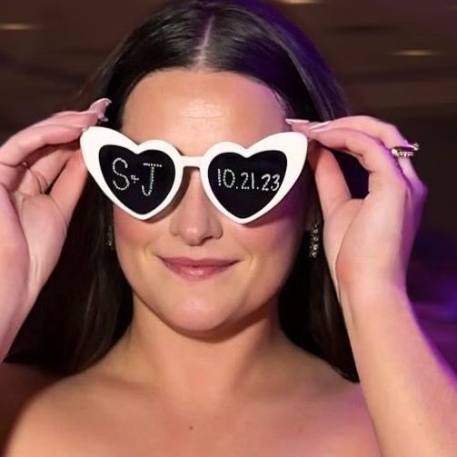 a woman holding up two heart shaped sunglasses