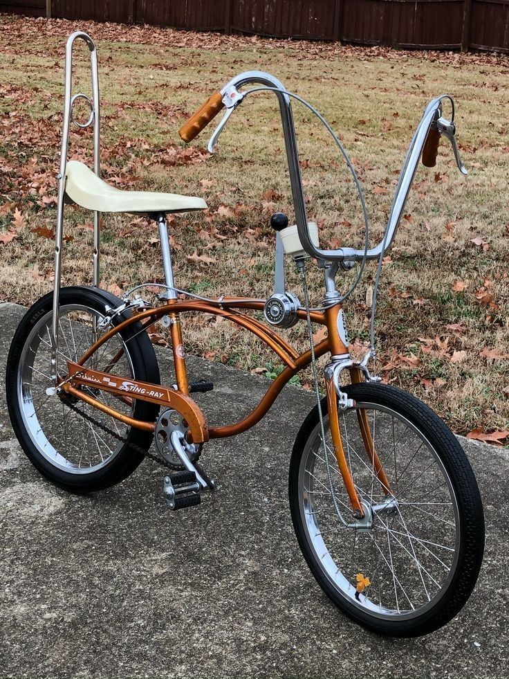 an orange bicycle parked on top of a sidewalk