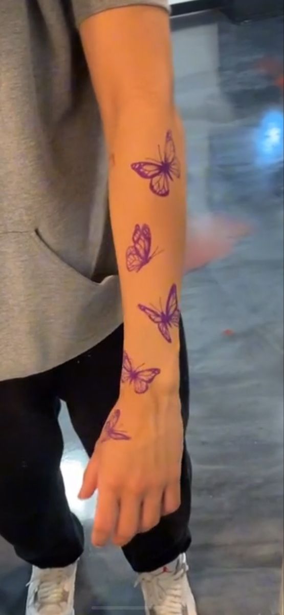 a person with a tattoo on their arm and butterfly tattoos on his arm, both hands