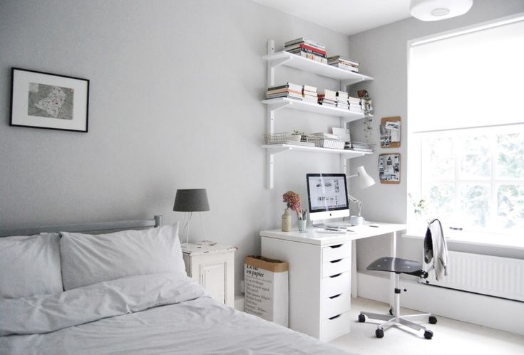 a bedroom with a bed, desk and bookshelf next to a large window