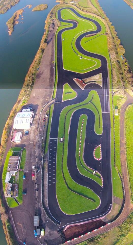 an aerial view of a race track in the middle of a field next to a body of water