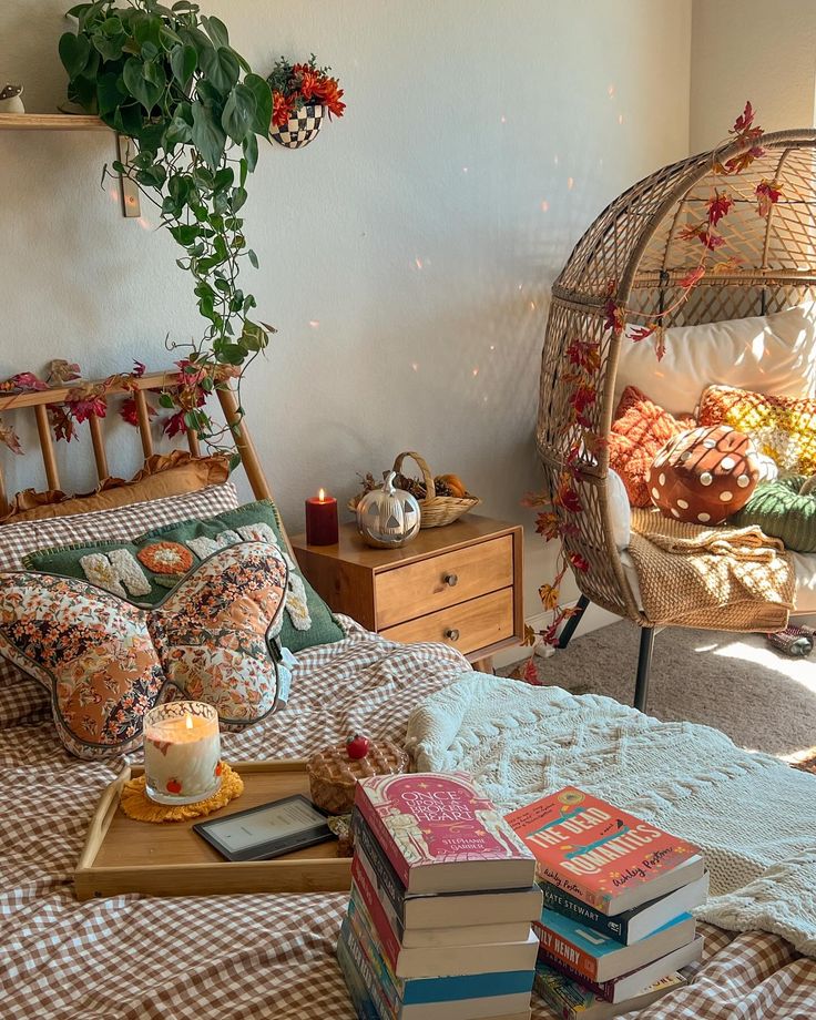 a bed with lots of books on top of it next to a chair and table