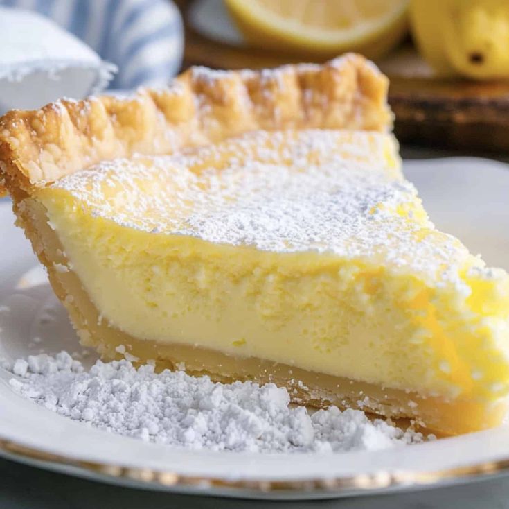 a slice of lemon pie on a plate with powdered sugar