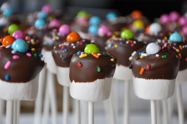 chocolate covered marshmallows with sprinkles and colored candies on them