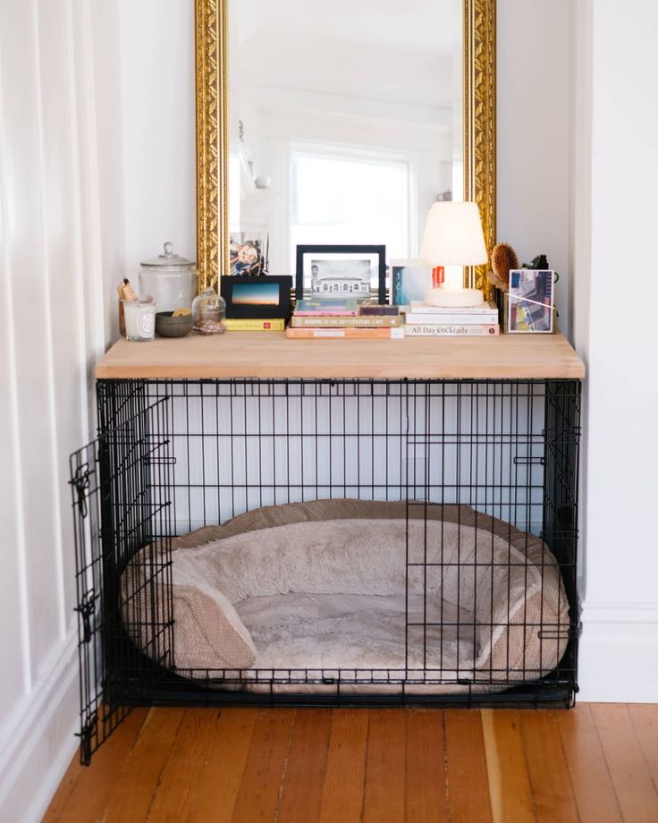 a dog bed in front of a mirror on top of a wooden table next to a lamp