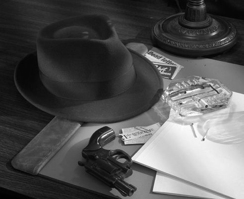 black and white photograph of hats, papers, keys and other items on a table