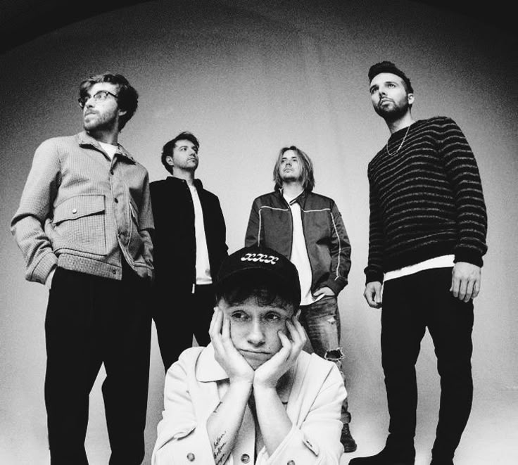 a group of young men standing next to each other in front of a white background