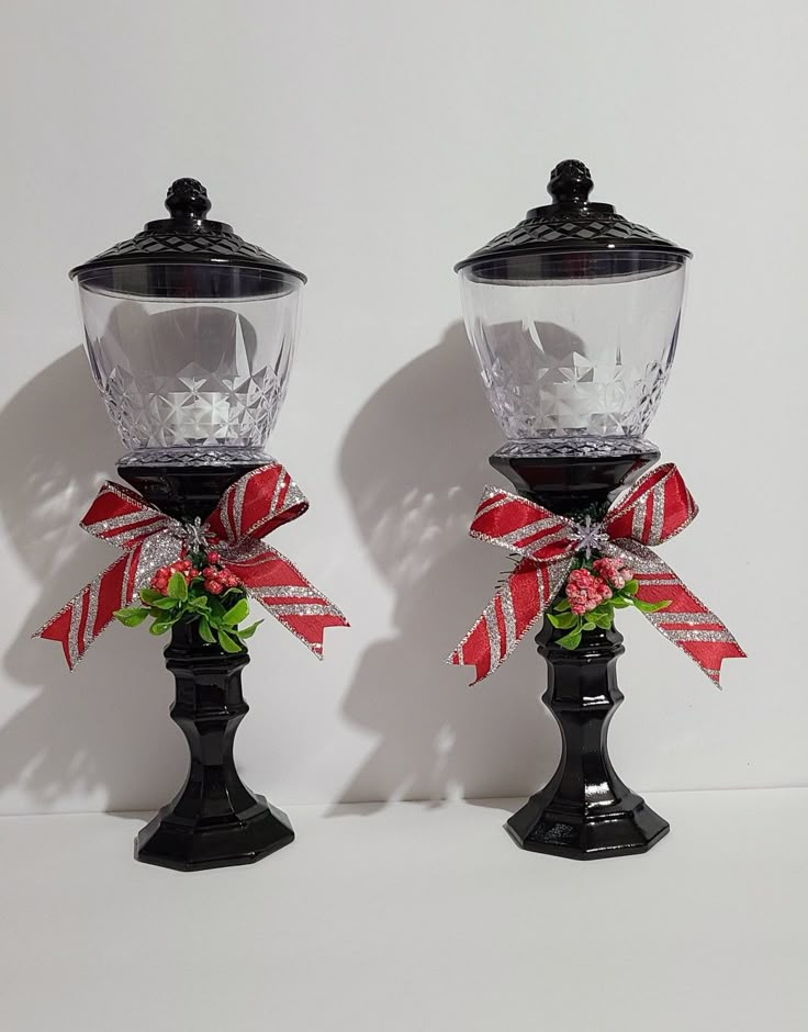 two glass vases with bows on them sitting next to each other in front of a white wall