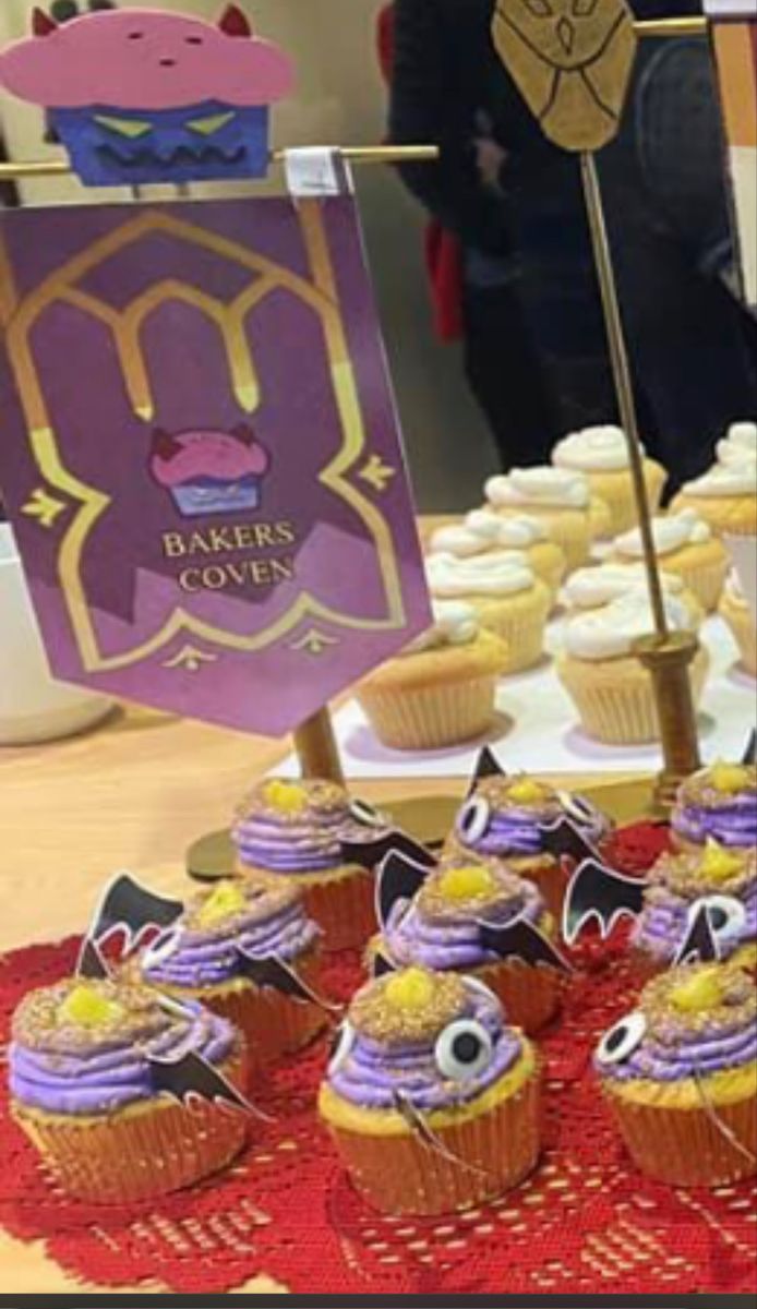 cupcakes are arranged on a red doily with purple frosting and gold decorations