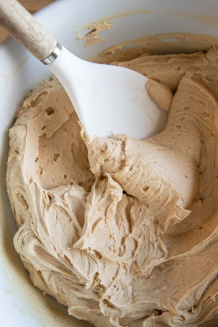 a white bowl filled with peanut butter and a wooden spoon