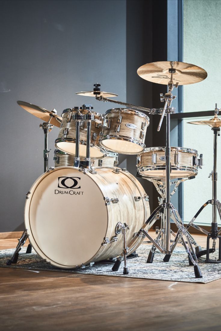 a drum set sitting on top of a hard wood floor next to a glass wall