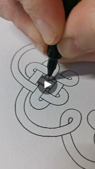 a person is writing on paper with a pen and inking the outline for an intricate design