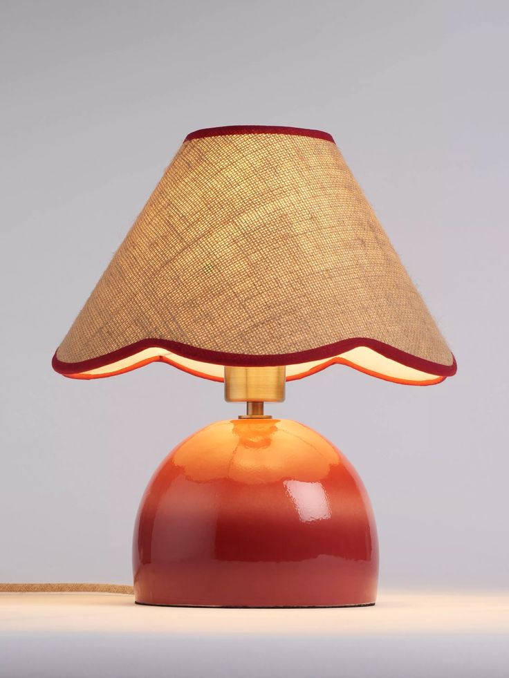 an orange lamp with a brown shade on the top and red base, sitting on a white surface