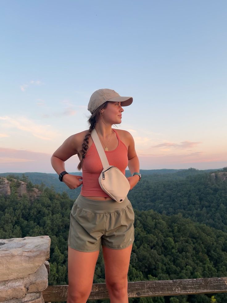 a woman standing at the top of a mountain with her hands on her hips and looking off into the distance