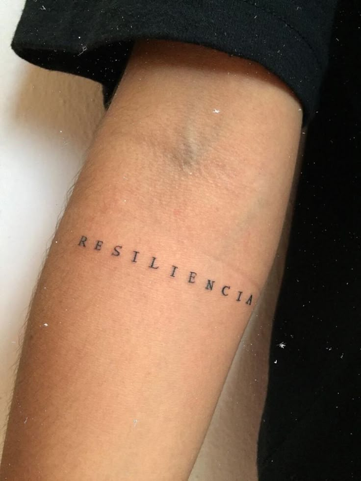 a woman's arm with the word resilicino tattooed on her left arm