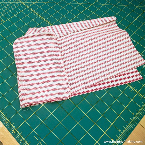 a pair of red and white striped cloths sitting on top of a cutting board