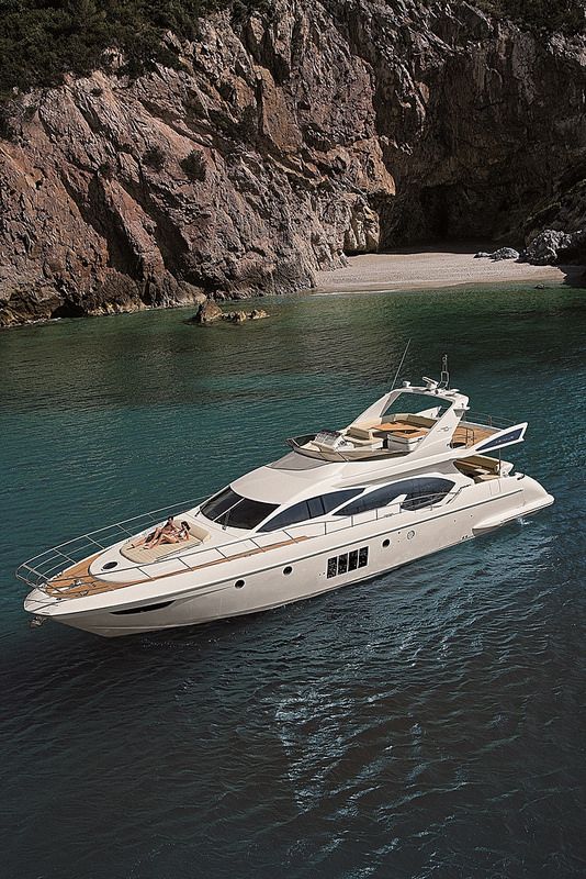 a white boat floating on top of a body of water next to a rocky cliff