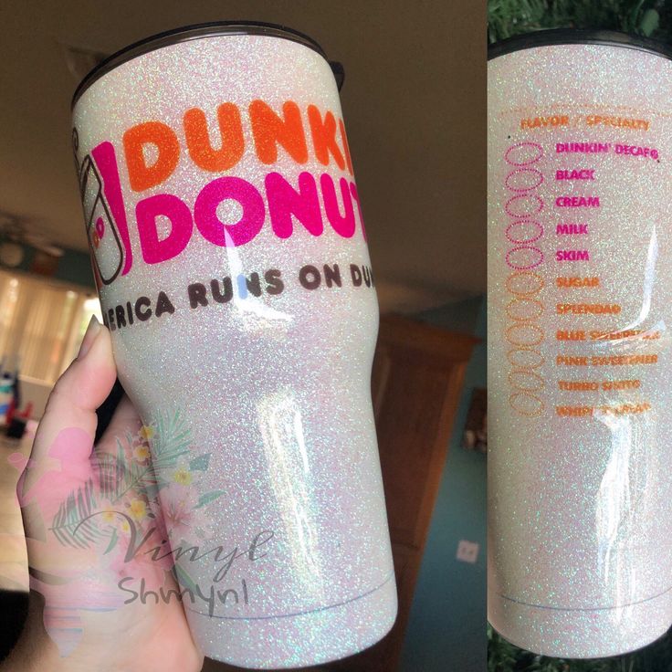 a person holding up a pink donut cup in their left hand and another one with orange writing on it