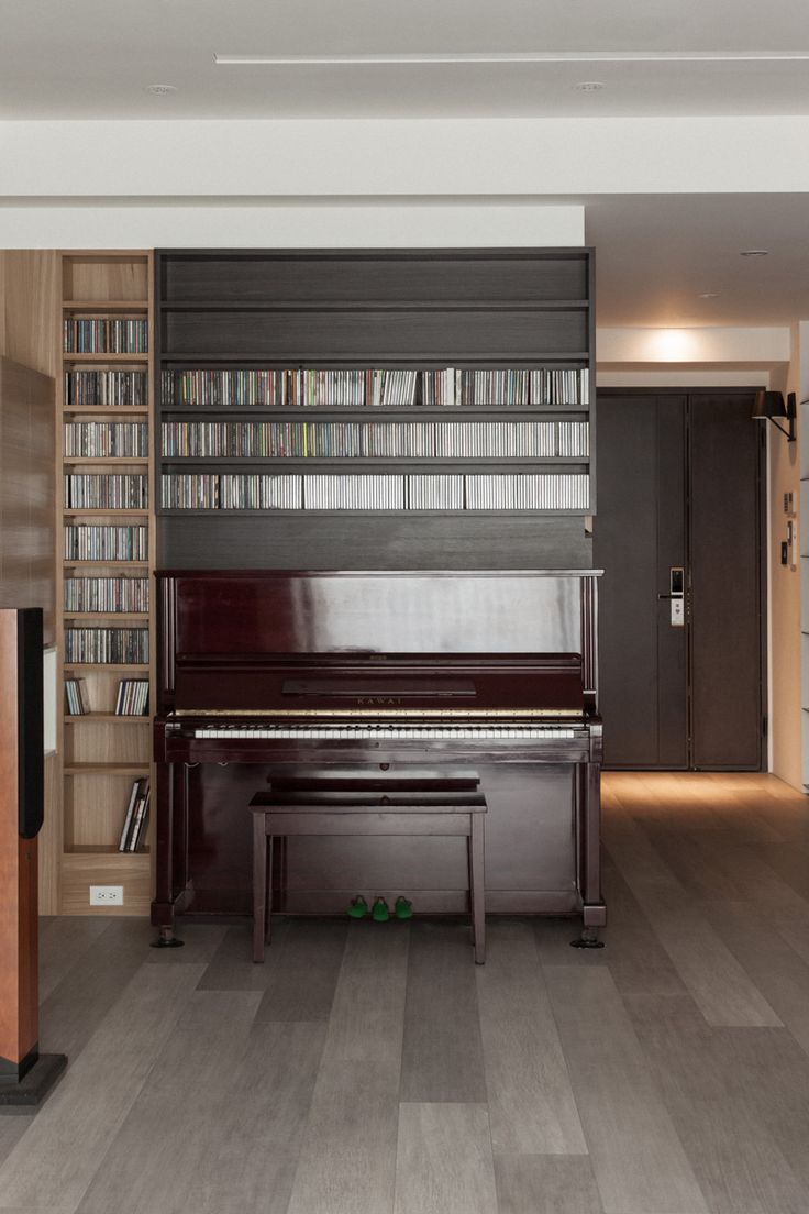 an empty room with a piano and bookshelves