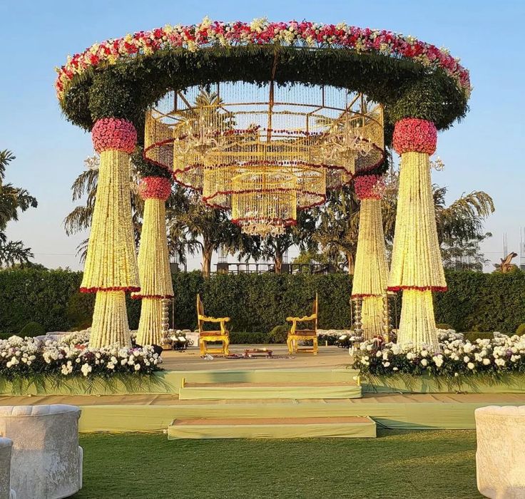 an elaborately decorated gazebo in the middle of a park with flowers and greenery