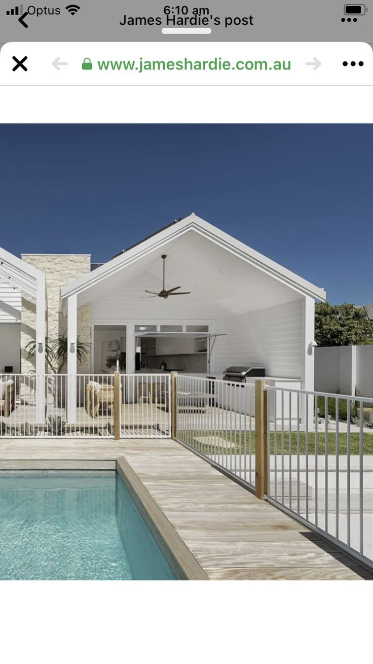 a house with a pool in front of it and a white fence around the pool