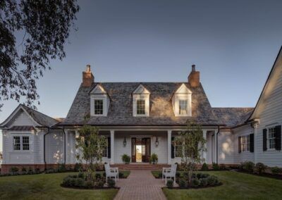 a white house with black shutters and brick walkway leading up to the front door