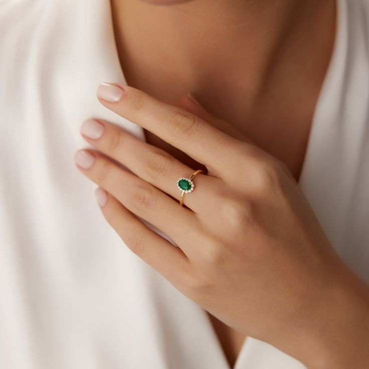 a woman's hand with a ring on it and a green stone in the middle