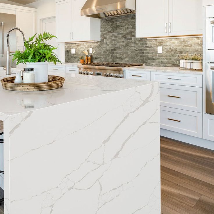 a large kitchen with white cabinets and marble counter tops, along with a center island