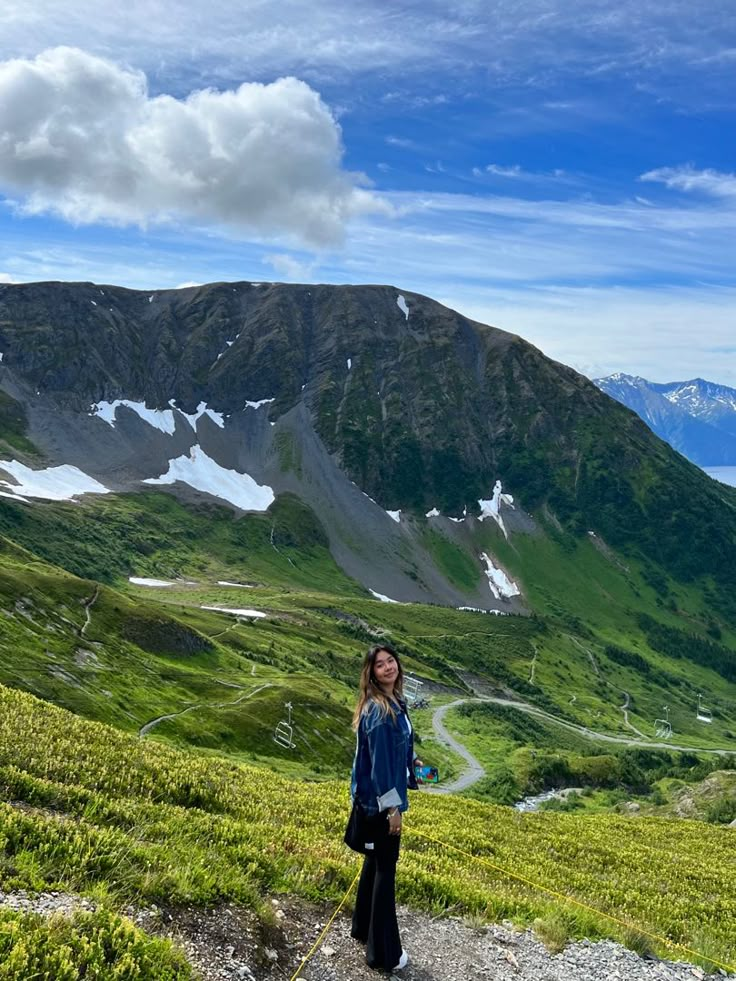 a woman standing on top of a lush green hillside