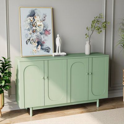 a green cabinet in a living room next to a potted plant and a painting on the wall