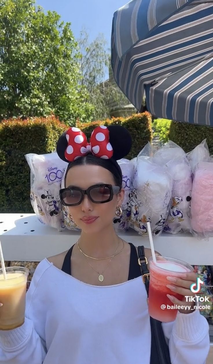 a woman in minnie mouse ears holding a drink