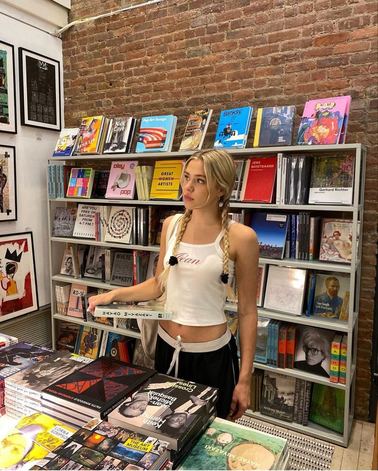 a woman standing in front of a bookshelf with many books on display behind her