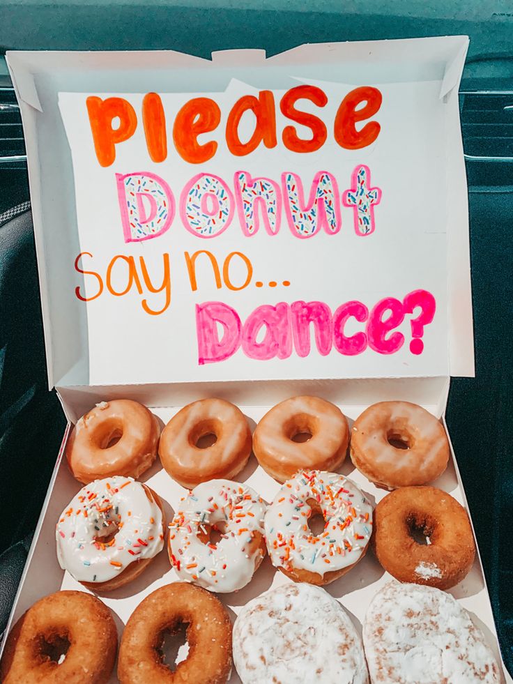 a box filled with lots of donuts sitting on top of a car seat next to a sign that says please donut say no dance