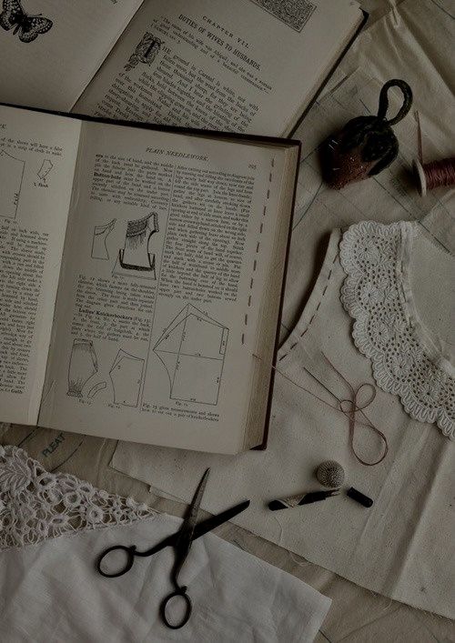 an open book sitting on top of a table next to some scissors and doily