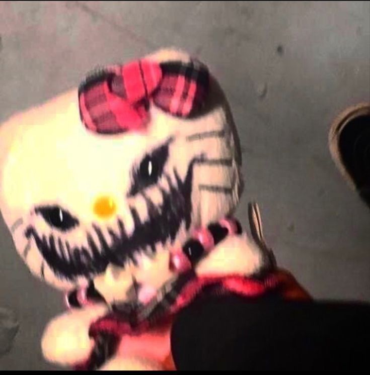 a hello kitty stuffed animal is being held up by someone's feet and shoes