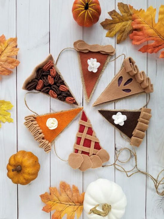 an assortment of fall decorations made out of felt and fabric on a white wooden surface