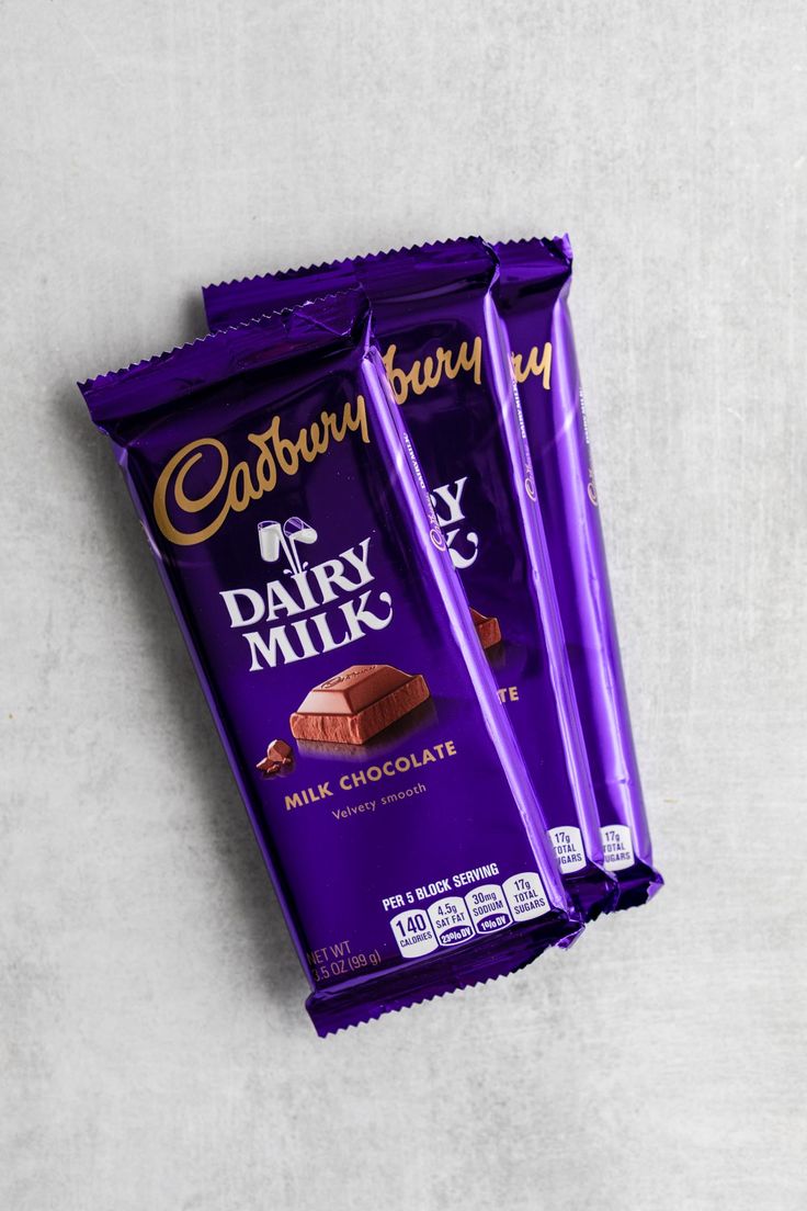 three cadburys dairy milk chocolate bars sitting next to each other on a white surface