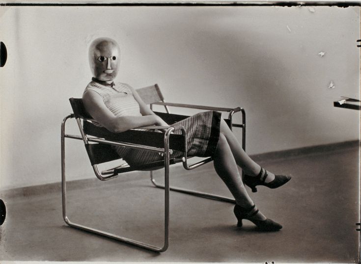 an old photo of a woman sitting in a chair with a weird face on her head